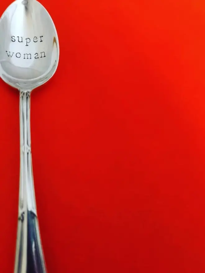 super woman handstamped onto a vintage silver plated teaspoons on a red background