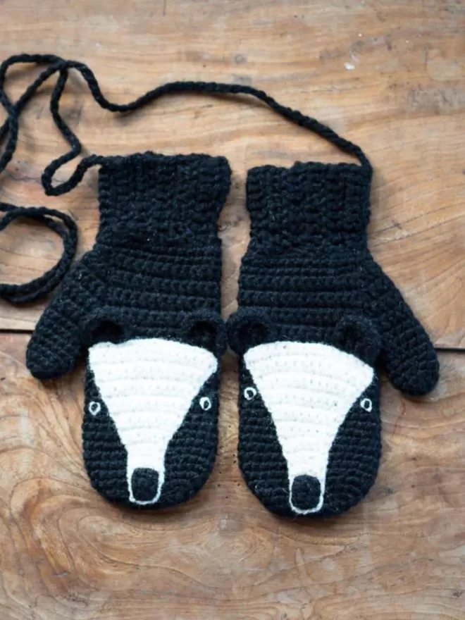 EKA Badger Animal Mittens seen on a wooden floor.