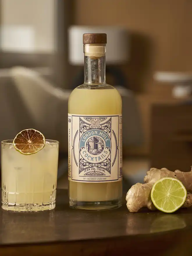 Tommy's Fizz London Mule Cocktail, a bottle of London Mule cocktail standing next to a short glass with ice.