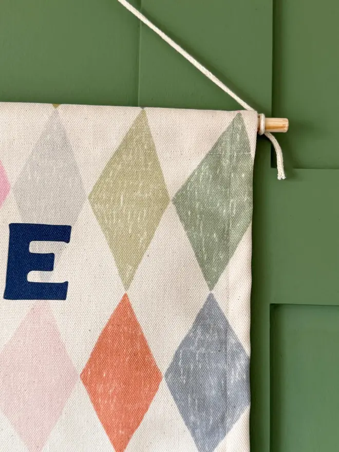 'Welcome To The Circus' Cotton Wall Hanging, hanging on a green wall. 