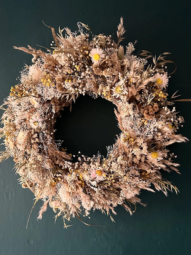 dried floral dried flower door wreath. a dried flower wreath made of various dried flowers and foliage hung on a forest green wall.