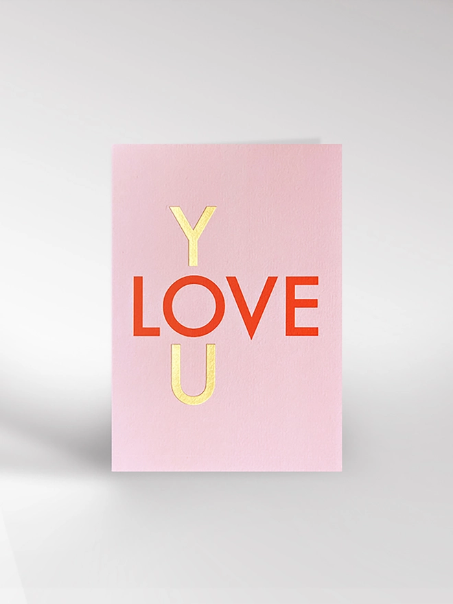 A typographic card with some gold foil blocking saying LOVE YOU