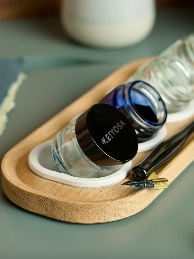 Versatilt Ink Stand. An ink stand in Marble White with a full pot of ink inside, shown tilted.
