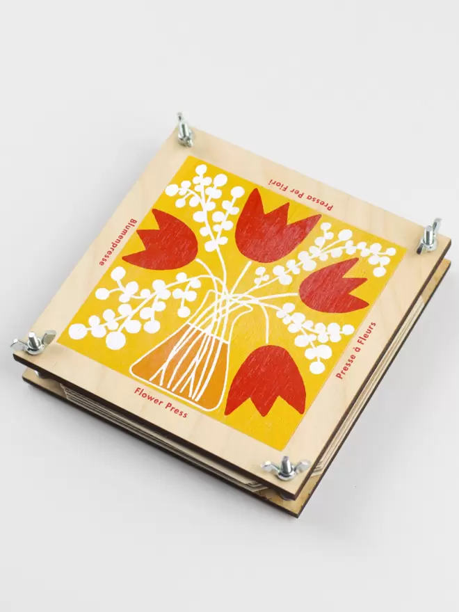 Square flower press with yellow and orange illustrated tulip design on the front.