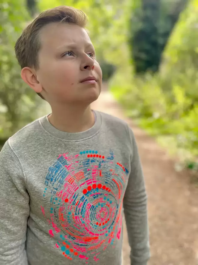 Boy wearing The 'Climber' Children's Printed Sweatshirt looking up at the sky.