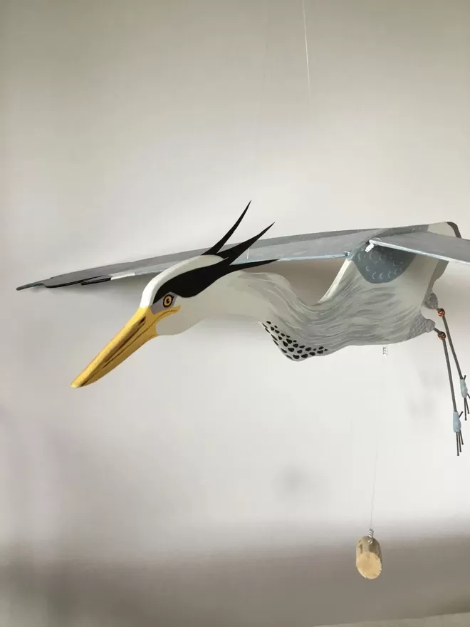 Flying heron hanging against a white wall