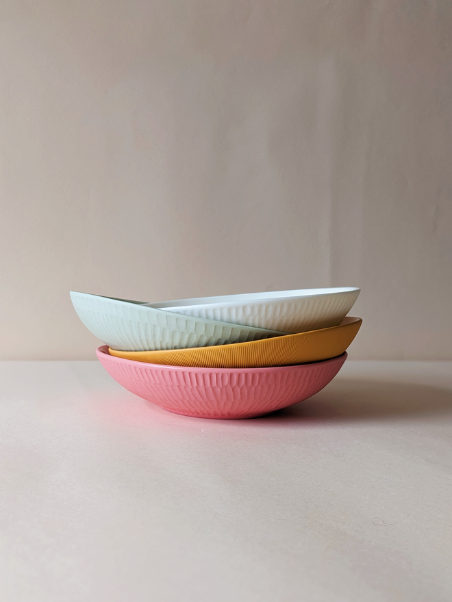 Stack of handmade porcelain pasta bowls with hand carved scalloped outside detail in white, Rockpool Green, Sunflower Yellow and Milkshake Pink