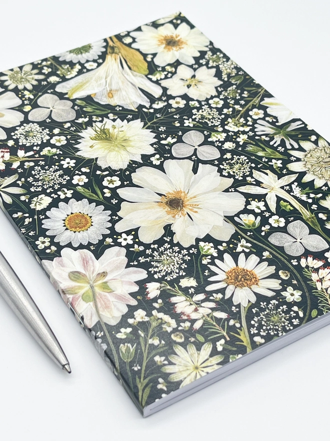 Notebook with flower print cover created from pressed flowers, with stapled spine.