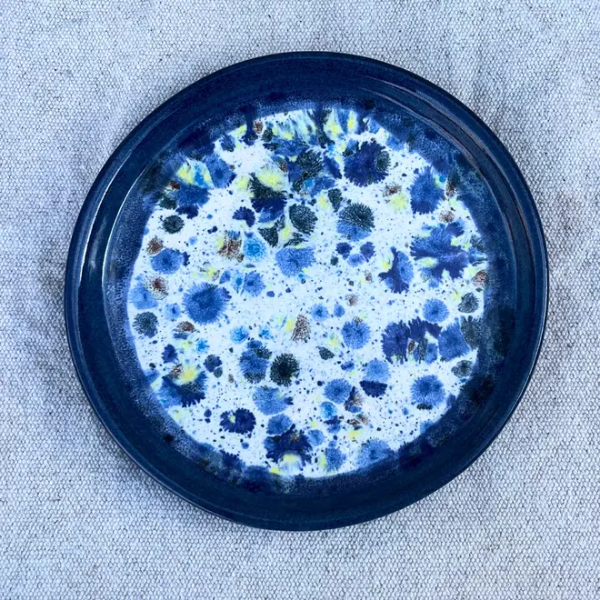 Shoreline Side Plate, a colourful plate placed on a stone surface.  
