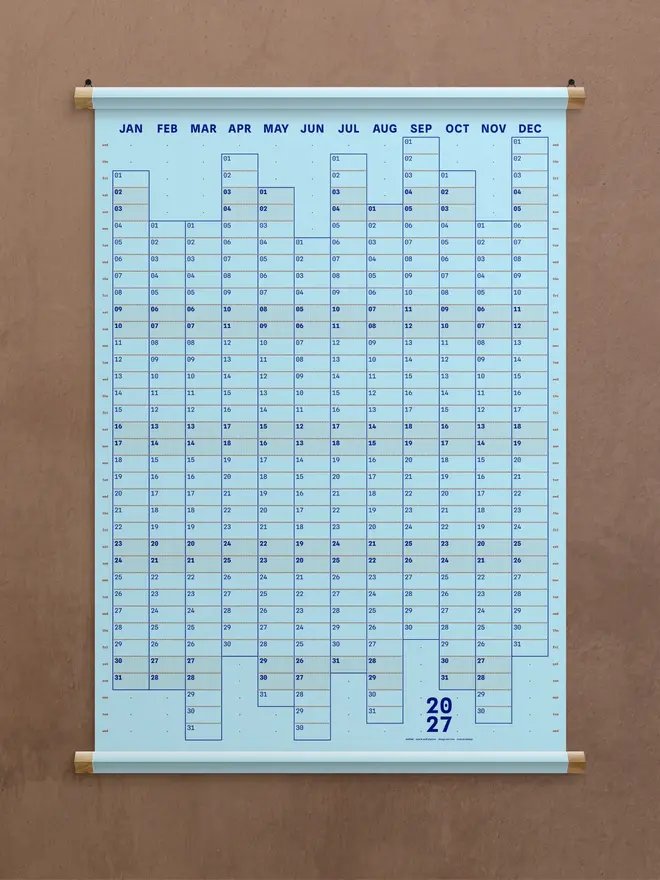 A blue 'sky' Dotline 2027 yearly wall planner on brown wall