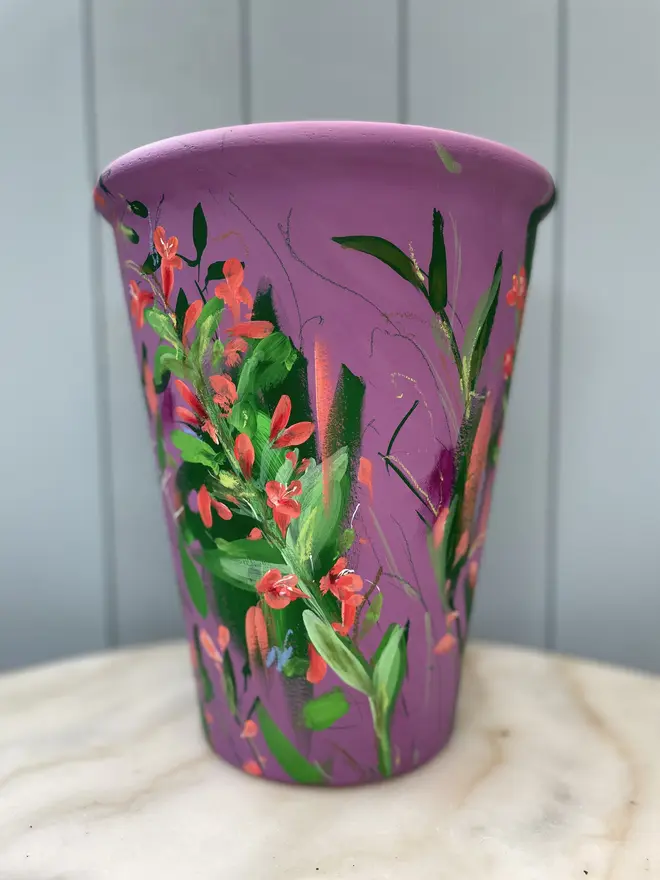 Unique hand-painted terracotta pot featuring twizzle coral flowers on a purple background