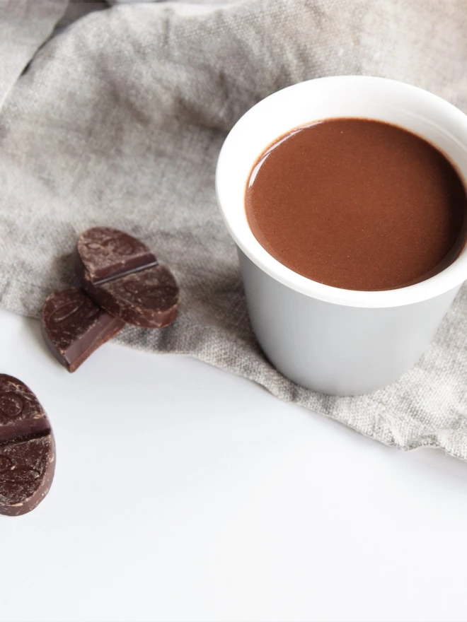 Small cup of vegan-friendly hot chocolate with pieces of chocolate