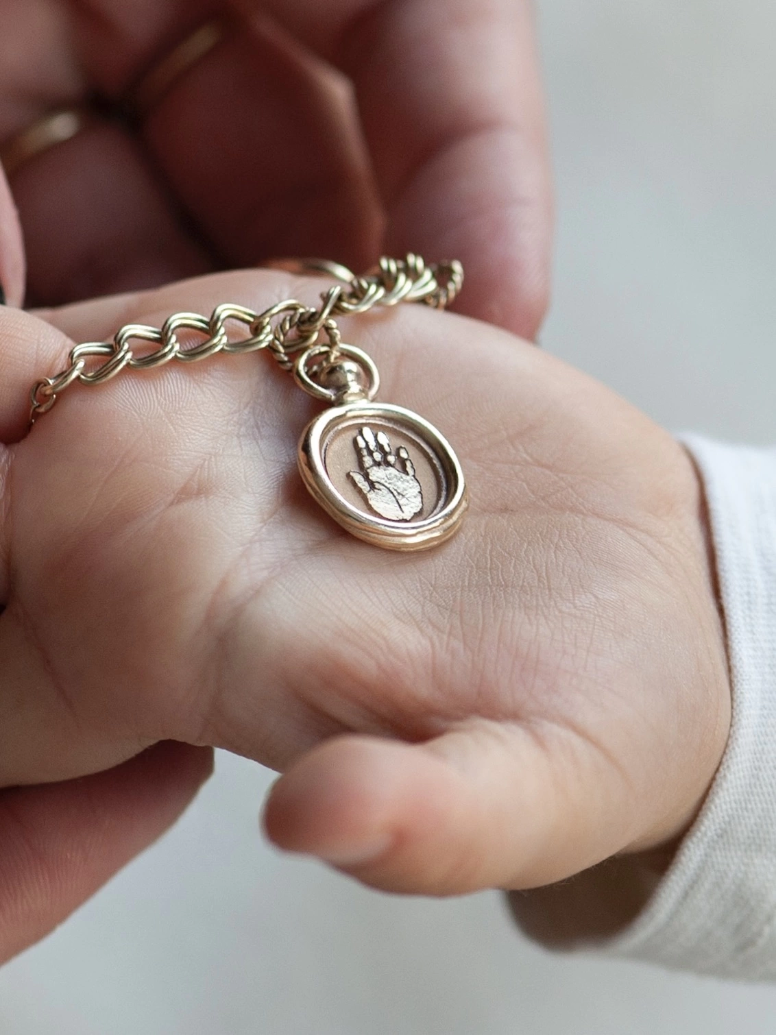 gold hand charm on a gold charm bracelet chain