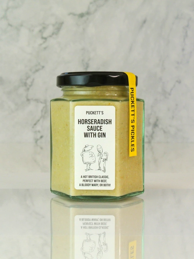 horseradish and gin sauce. a jar of horseradish sauce photographed on a marble background.