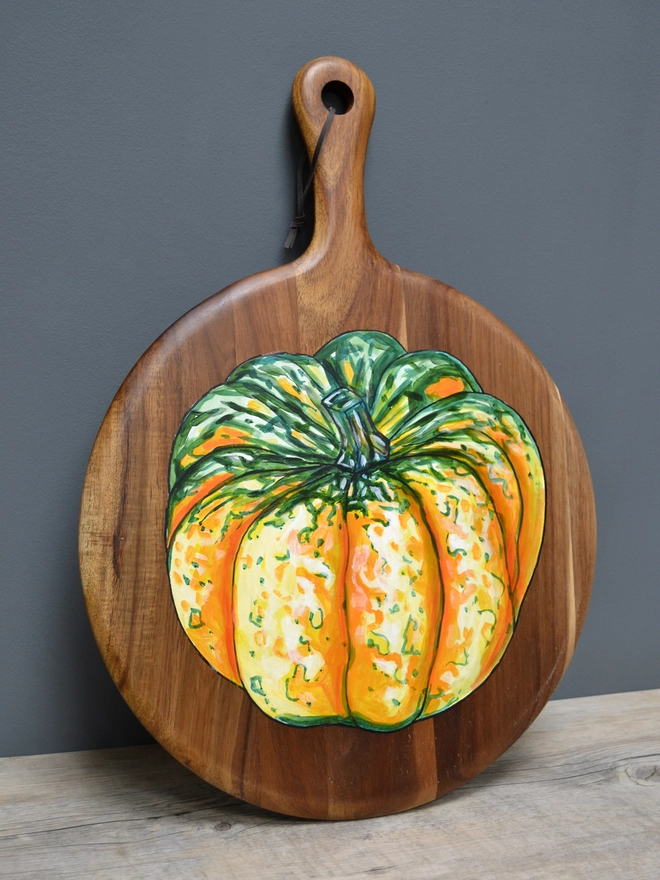 Wooden serving board with a handpainted design of a carnival squash