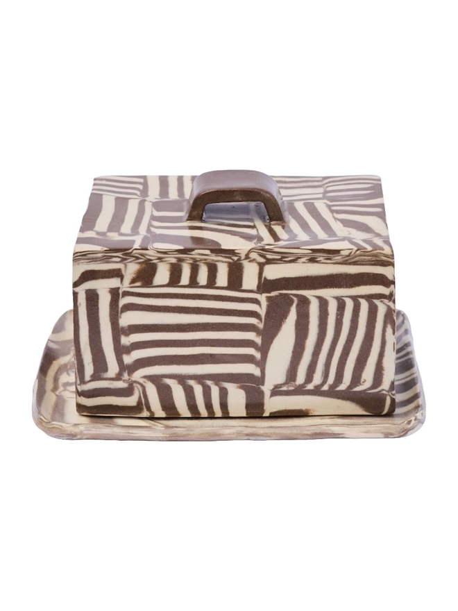 Striped Butter Dish, a colourful striped butter dish sitting on a white surface against a plain backdrop. 