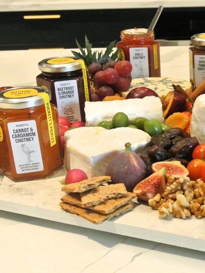 carrot and cardamom chutney. a charcuterie board surrounded by jars of artisan pickles.