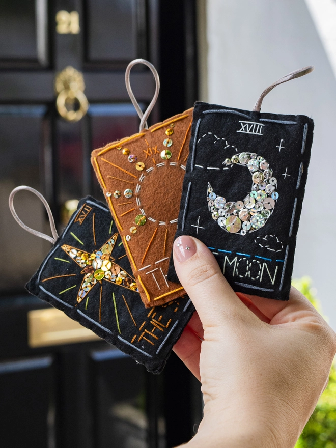 A handcrafted felt ornament with sequins and embroidery depicting "The Star" tarot card. Also accompanied by “The Sun and The Moon”