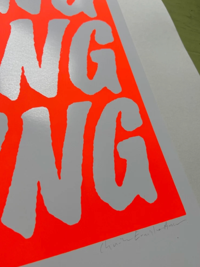Fluoro Amazing Print. Close up of a vibrant orange background with AMAZING written five times.