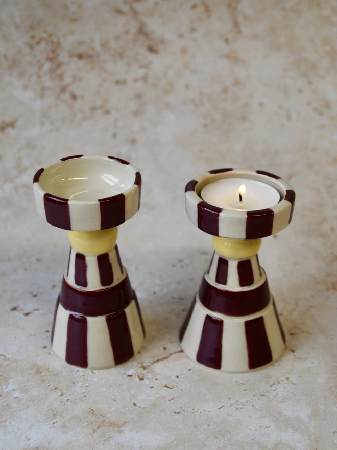 Pair of handmade striped ceramic tea light holders in burgundy and cream tones, photographed side by side
