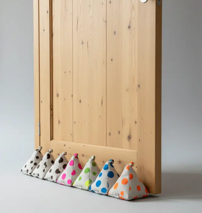 Hand Painted Linen Sustainable Doorstop In Polka Dot Print in various colours, lined up against wooden door