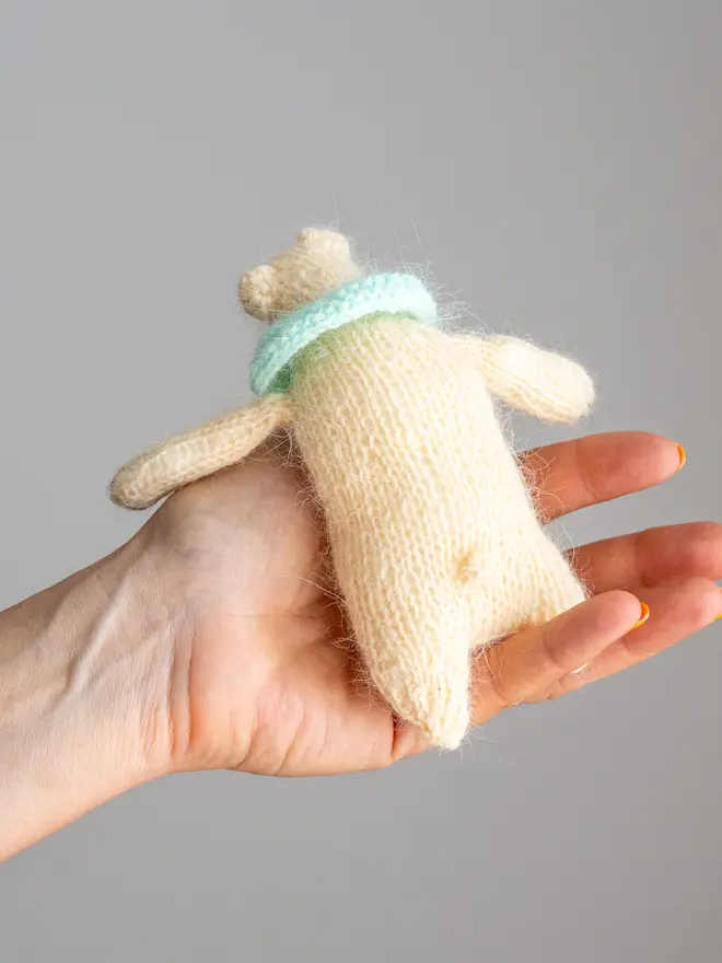 Ottilie The Bear Cashmere Figure, a cashmere bear held by a person against a grey backdrop. 