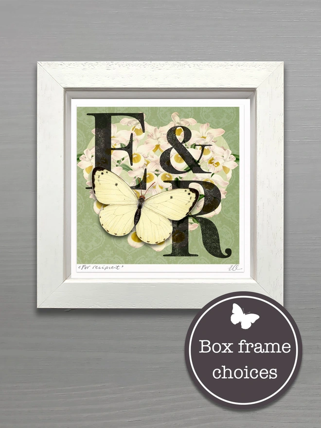 A framed, mint green wedding, monogram card, showing the initials E and R. The initials are black and placed on a white orchid heart. A white 3D hand cut paper butterfly sits on the bottom left of the heart. The card has the option to personalise further with the names of the couple, handwritten and the wedding date in the bottom, border of the card.