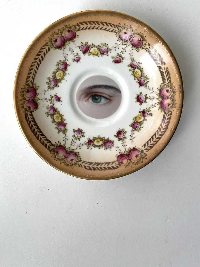 vintage plate with an ornate border, with a printed vintage illustration of an eye in the middle
