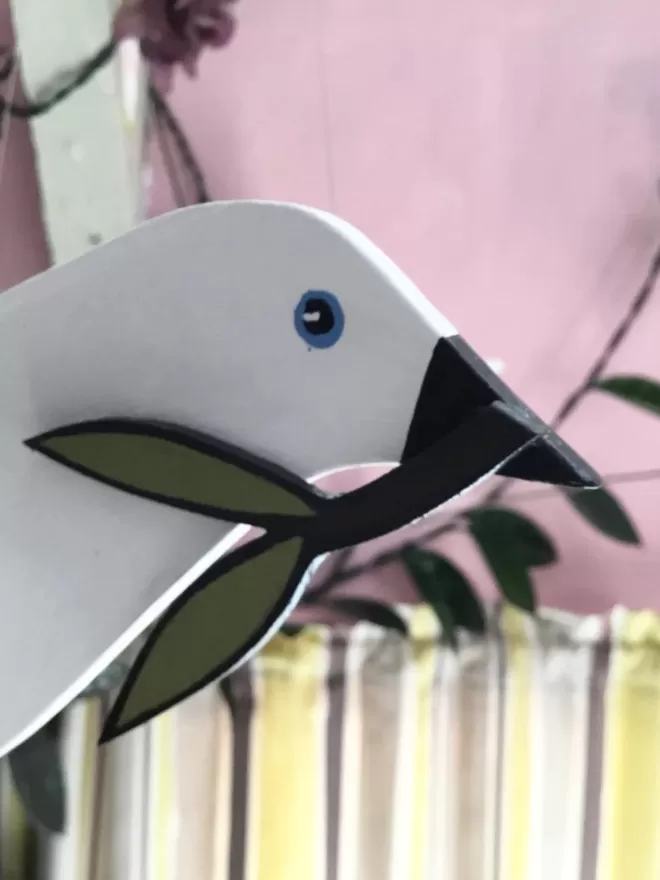 Close Up of Dove's face holding an Olive Branch 