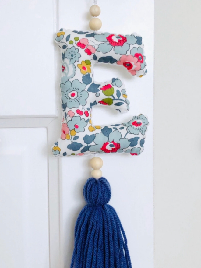 Liberty Hanging Initial Ornament. An initial hanging from a door in a floral fabric.