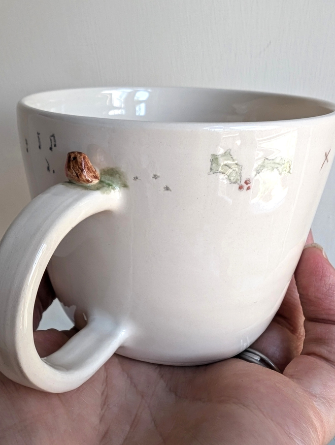 ceramic cup with a tiny pottery robin on the handle with musical notes hand painted christmas holly and tiny bird prints