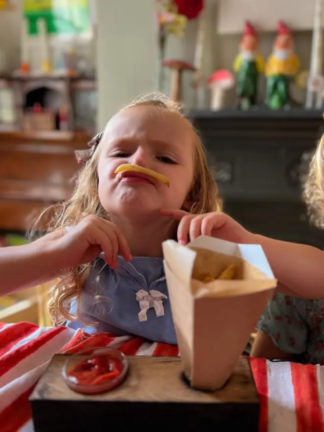Funny pic of young child  resting a chip like a moustache showing also cone chip and dip holder