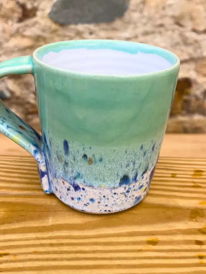 Shoreline Standard Mug, a colourful mug placed on a wooden surface. 