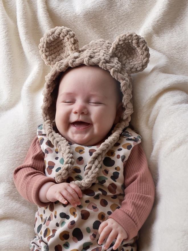 Happy baby wearing handmade teddy bear bonnet