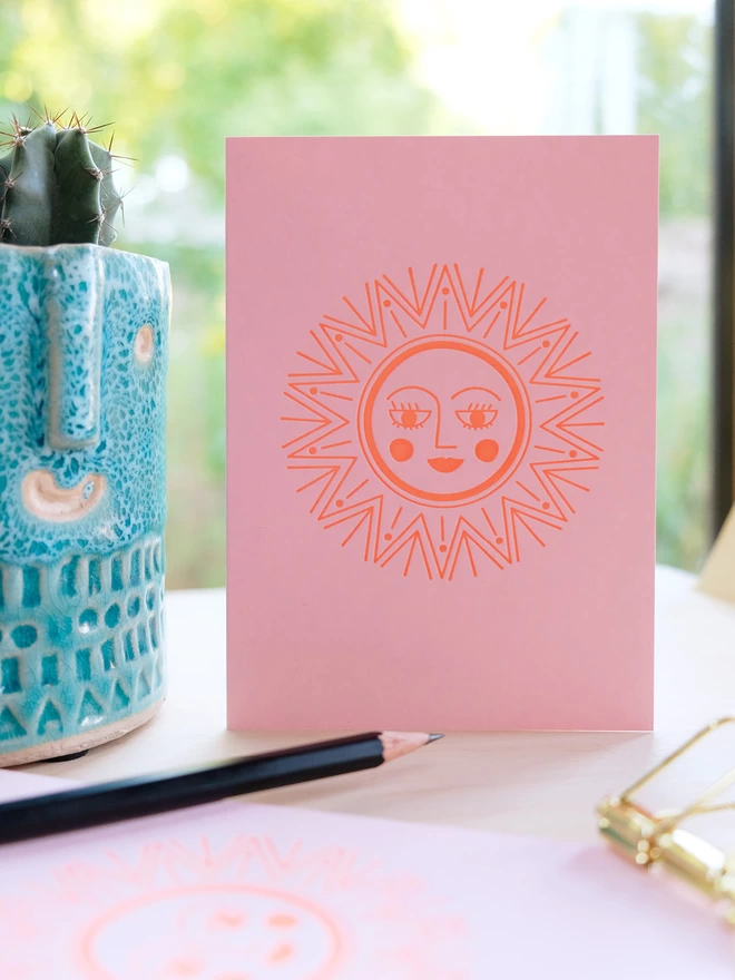 Front on view of sunshine letterpress card on table with cactus and pencil.
