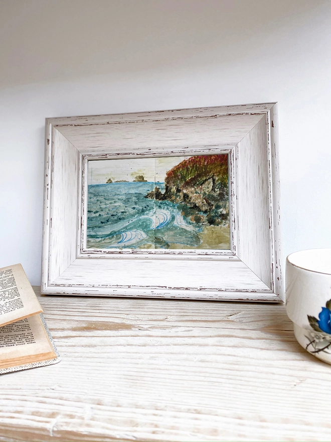 a framed painting of waves crashing on the shore