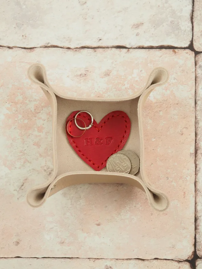 A mini square valet tray in natural cream with a red love heart in the base. The heart is personalised with the initials H&F and holds spare change and two wedding rings inside.
