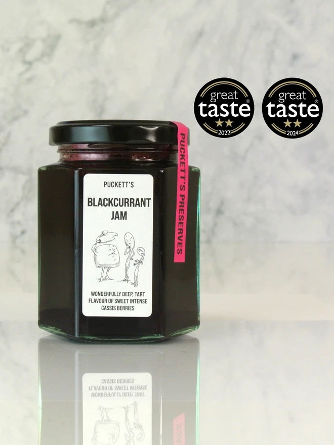 brbritish blackcurrant jam. a jar of jam photographed against a marble background.