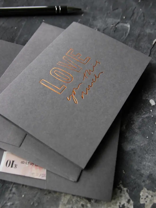 Hand foiled cash card or money wallet in a smoke grey colour in shiny bronze foil text which says ‘love you this much’.