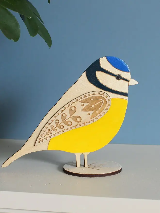 Standing Wooden Blue Tit, yellow wooden bird decoration standing on a platform. 