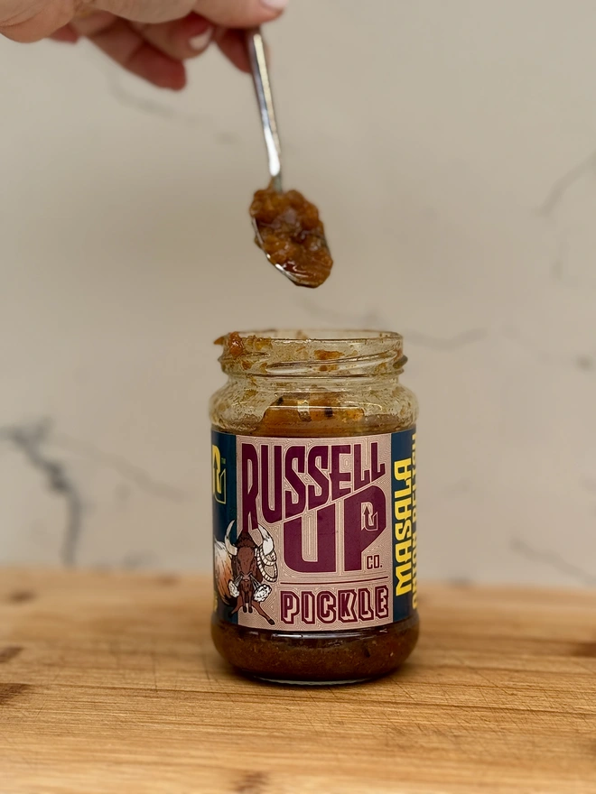 father's day pickles - cheese set. a jar of masala onion relish photographed being spooned out.
