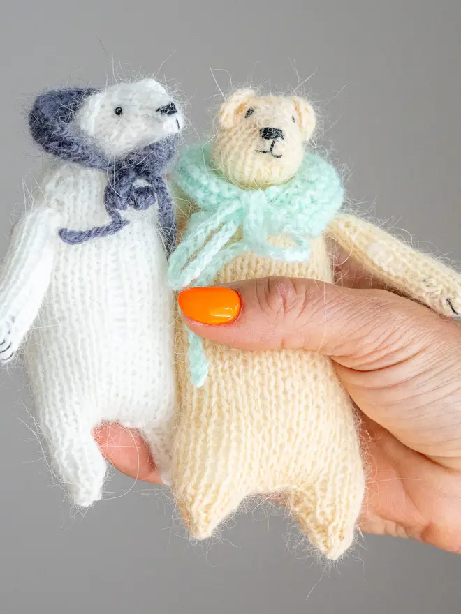 Ottilie The Bear Cashmere Figure, a pair of cashmere bears held by a person against a grey backdrop. 