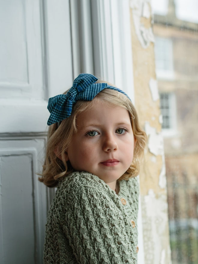 Blue Gingham Alice Band on little girl by a window