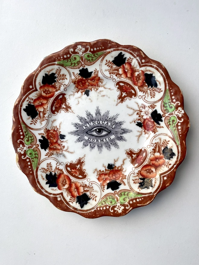 an ornate vintage plate with detailed border and in the centre an vintage illustration of an eye