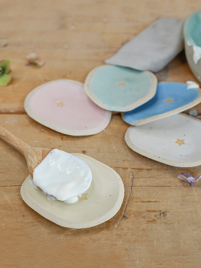 Ceramic spoon rests in light yellow, pale pink, mint green, cornflower blue and off-white with singular star detail on wooden table