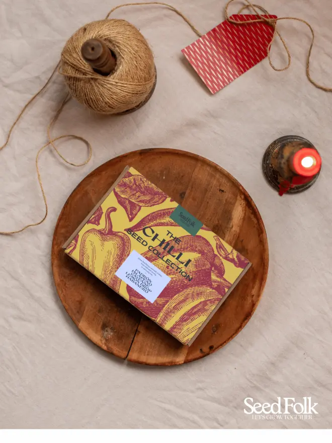 The Chilli Seed Collection Box. Beautiful box illustrated in yellow and red botanical print, photographed on a wooden tray. 