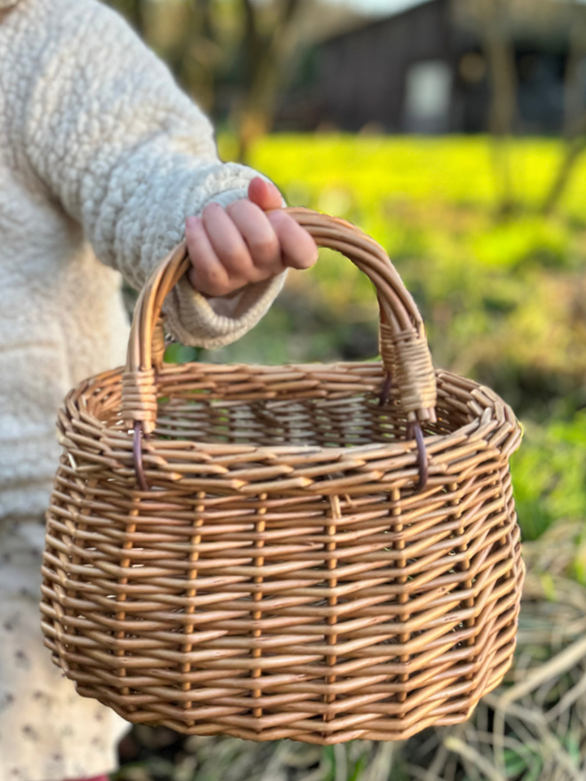 Child holding swing handled wicker basket up close