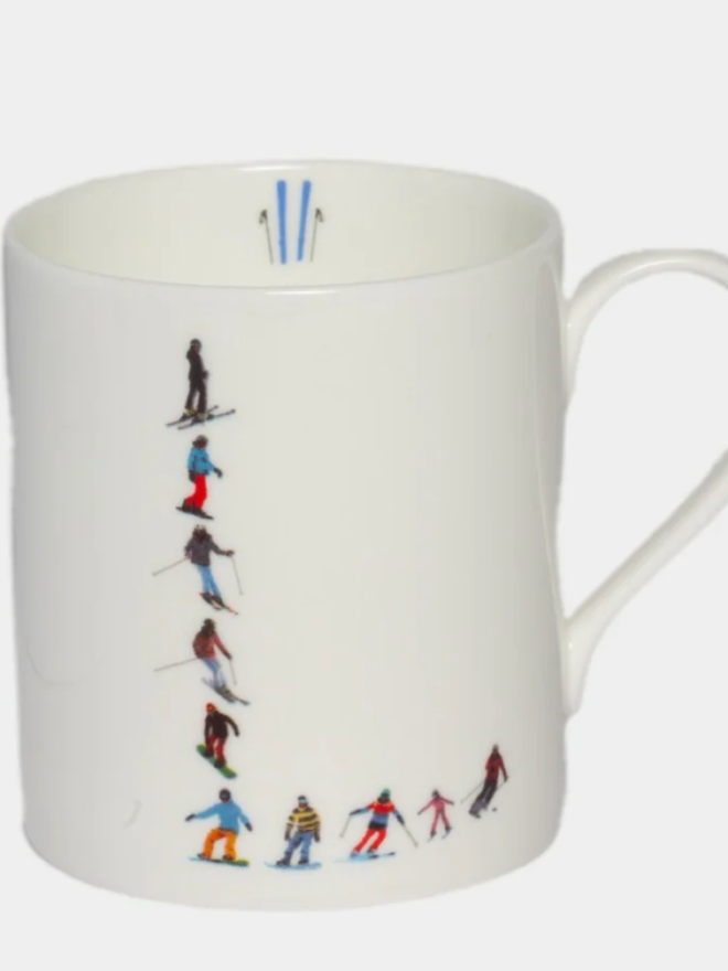 A simple white mug illustrated with an ‘L’ made of small, multicoloured skiers. The mug is set against a plain, white background.