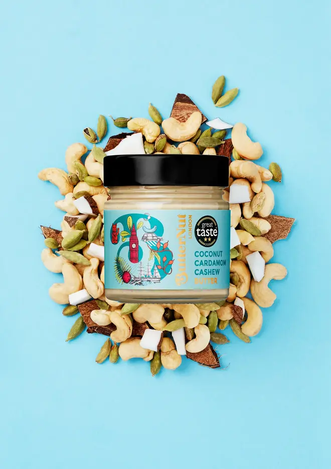 coconut cardamom cashew butter. a jar of nut butter photographed against a light blue background, surrounded by cashews and cardamom pods.