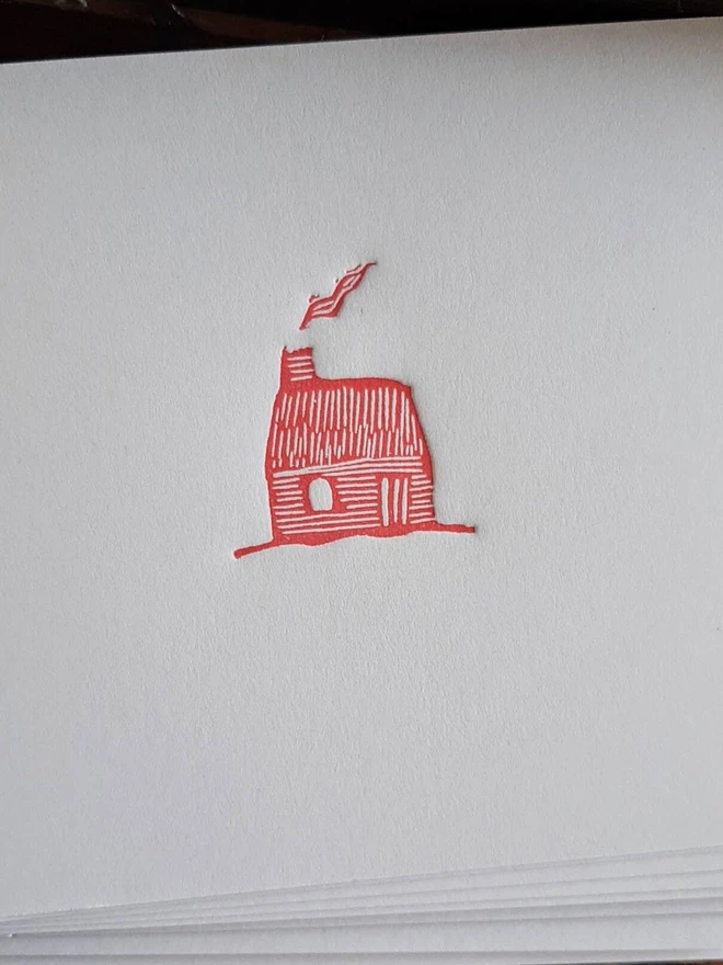 Tiny Red Cottage Letterpress Handprinted Greetings Card, a white card with a tiny red cottage design in the centre. 